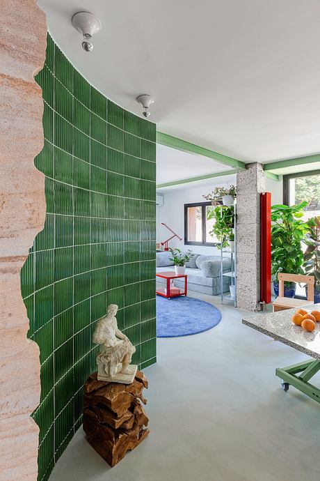 Vibrant green tile wall, modern furnishings, and lush plants create a cozy, nature-inspired space.