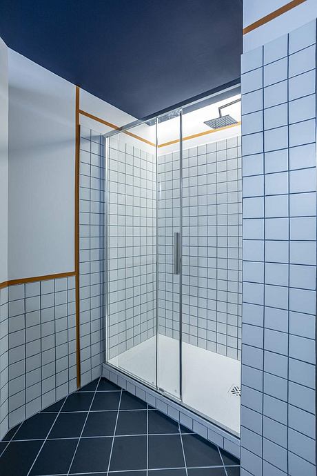 Modern shower enclosure with tiled walls, glass door, and recessed lighting fixtures.