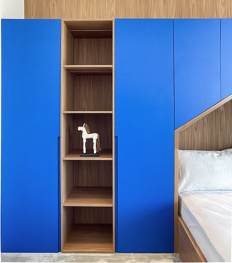 Minimalist wooden shelving nook with a small horse figurine against bold blue wall panels.