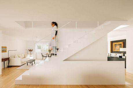 Sleek, modern interior with minimalist staircase and contrasting artwork in living room.