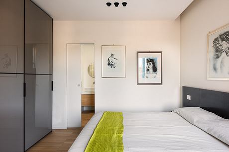 Well-designed bedroom with sleek black furniture, framed artwork, and hints of natural wood accents.