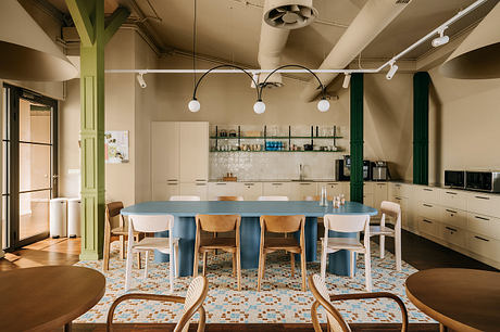 A spacious loft-style kitchen with industrial-style lighting, wooden furniture, and vibrant mosaic tiles.