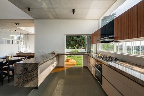 A modern, open-plan kitchen with sleek cabinetry, granite countertops, and expansive windows.