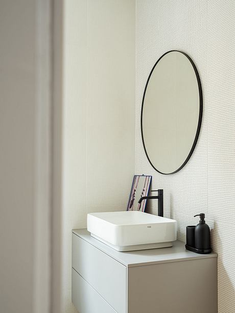 A modern bathroom vanity with a sleek, oval-shaped mirror and minimalist accessories.