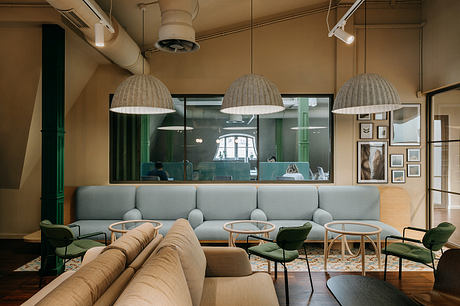 Cozy lounge with modern furniture, pendant lights, and glass partitions creating an inviting atmosphere.