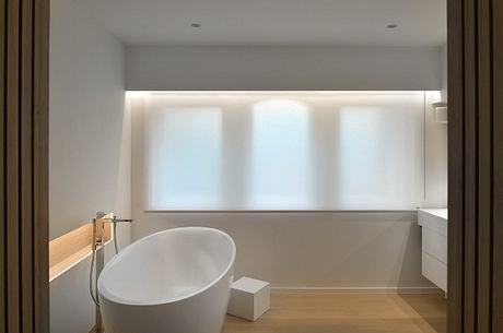 A modern, minimalist bathroom with a freestanding tub, wooden accents, and ample natural light.