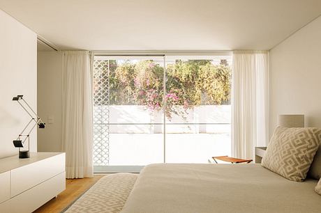 Spacious bedroom with large windows overlooking a lush, blooming garden.