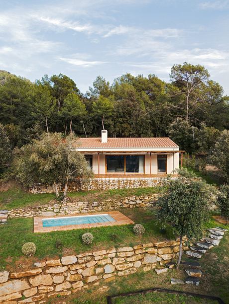 A charming stone house nestled in lush greenery, featuring a pool and terrace with scenic views.