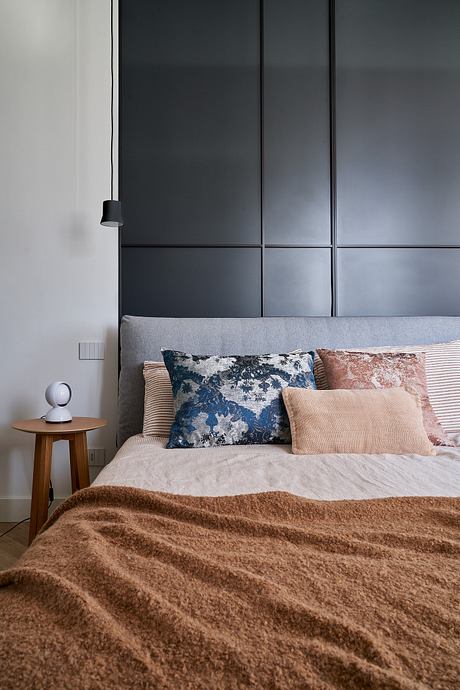 Modern bedroom with sleek black cabinetry, layered neutral bedding, and plush throw.