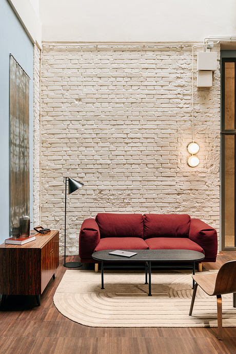 Cozy living room with exposed brick wall, red sofa, and mid-century inspired decor.