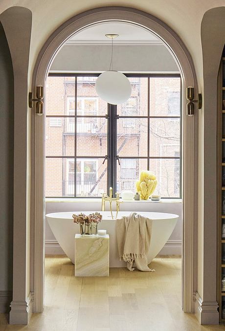 Arched window frames, freestanding bathtub, and decorative elements in a luxurious bathroom.