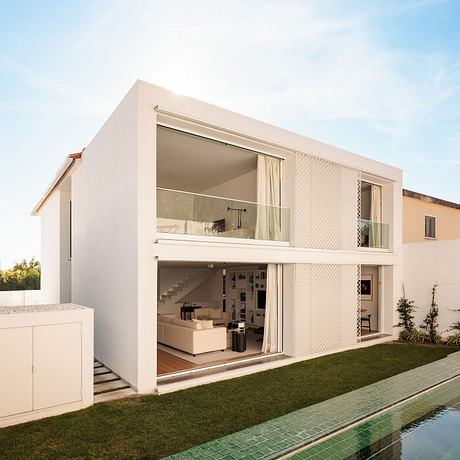 Modern, minimalist two-story house with clean lines, large windows, and a pool.