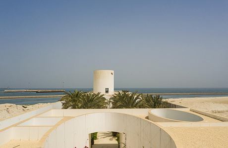 Circular walkway surrounded by lush vegetation leads to a white, cylindrical tower.