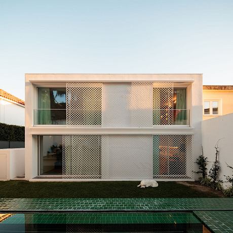 A modern two-story house with a distinctive pattern of metal screens covering the facade.