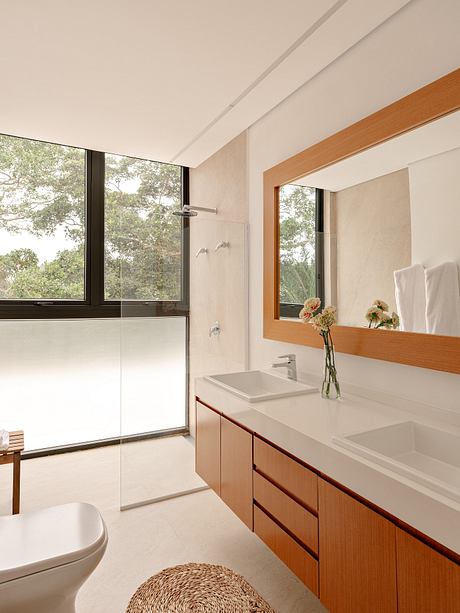 Minimalist bathroom design with wooden vanity, large mirror, and lush green view.