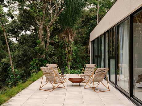 Tranquil outdoor seating area surrounded by lush greenery and glass walls.