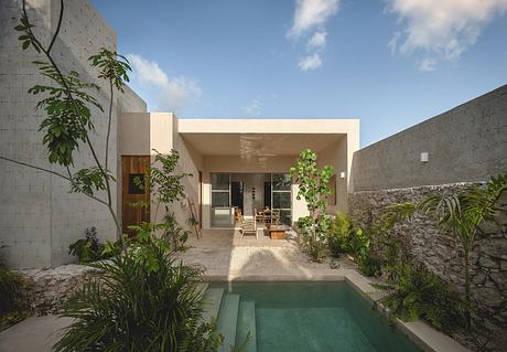 Minimalist modern home with open-air living area, pool, and lush tropical foliage.