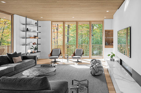 Modern living room with floor-to-ceiling windows, wood-paneled ceiling, and sleek furniture.