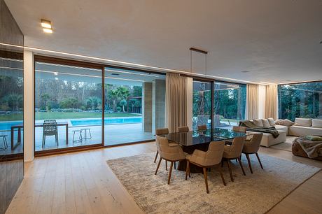 Spacious modern dining area with large windows overlooking a serene outdoor pool.
