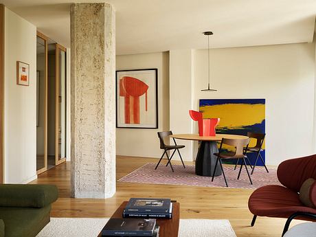 Minimalist interior with exposed concrete column, abstract art, and modern furnishings.