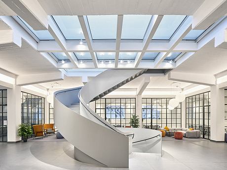 Sleek, modern office lobby with spiral staircase, glass skylights, and minimalist furniture.
