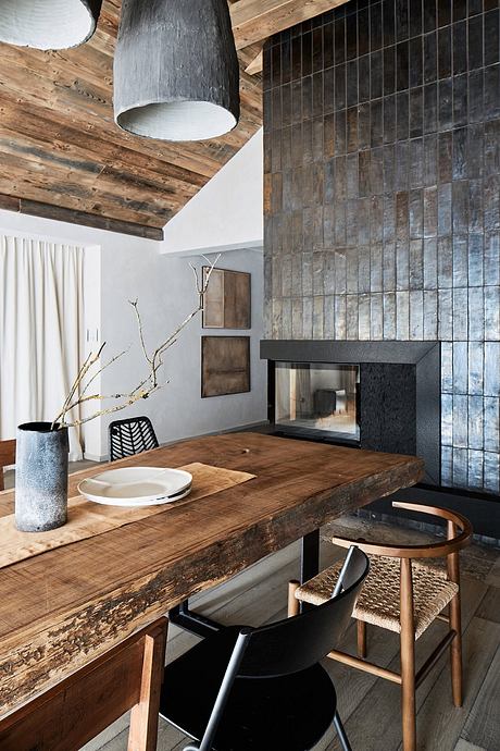 Rustic wooden ceiling, textured stone wall, minimalist dining area with wooden table and chairs.