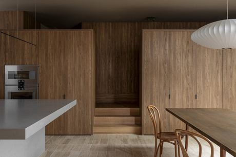 Warm wood tones, sleek kitchen appliances, and a cozy dining area create a modern, inviting space.