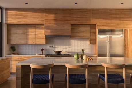 Warm-toned wood kitchen with sleek cabinets, island, and modern appliances.