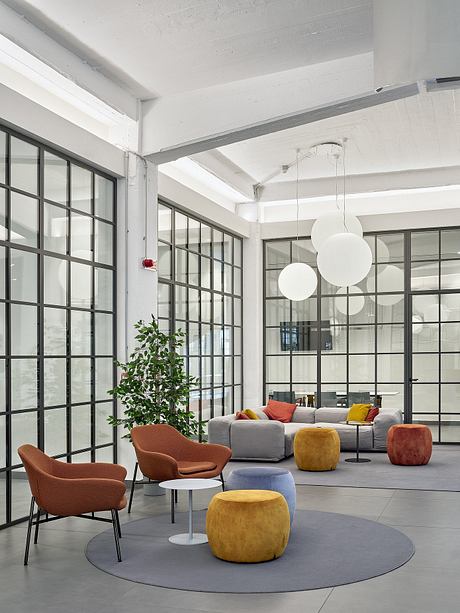 Spacious open-plan lounge with large windows, modern furniture, and hanging light fixtures.