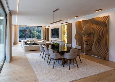 Spacious, modern living and dining area with sleek wooden wall panels, large windows, and plush furnishings.