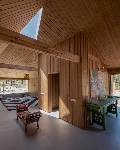 A rustic wooden interior with vaulted ceilings, colorful artwork, and a patterned rug.