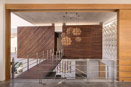 Wooden framework, suspended woven light fixtures, and a modern staircase with metal rails.
