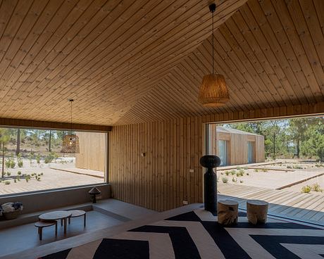 Warm, rustic interior with geometric patterned rug, wood-paneled walls, and pendant lighting.