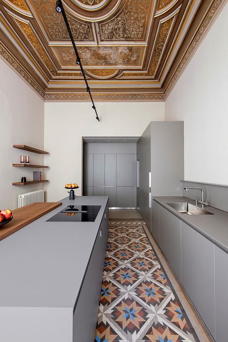 Ornate, gilded ceiling with intricate patterns contrasts with modern, minimalist kitchen design.