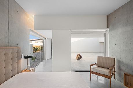 Minimalist interior with concrete walls, wooden furniture, and expansive windows.