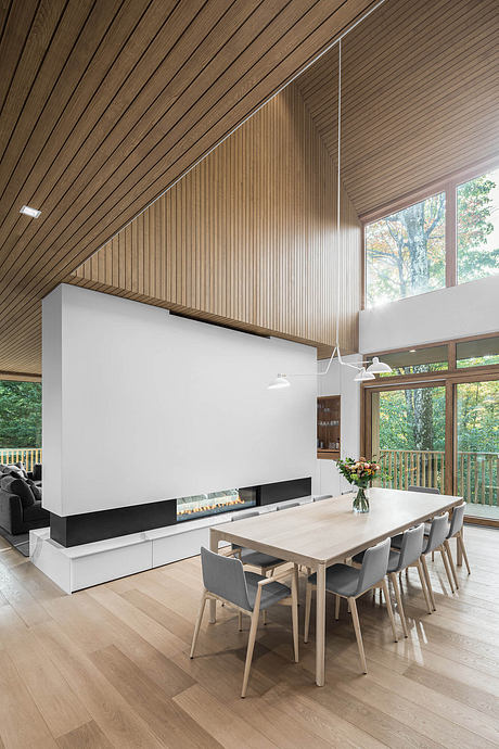 Modern, open-concept dining area with wood-paneled ceiling, large fireplace, and scenic views.