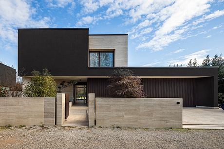 Modern, minimalist home design with clean lines, dark exterior, and stone accents.