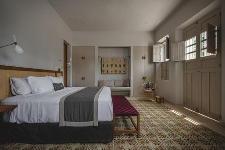 A modern bedroom with warm wooden accents, patterned flooring, and a cozy seating area.
