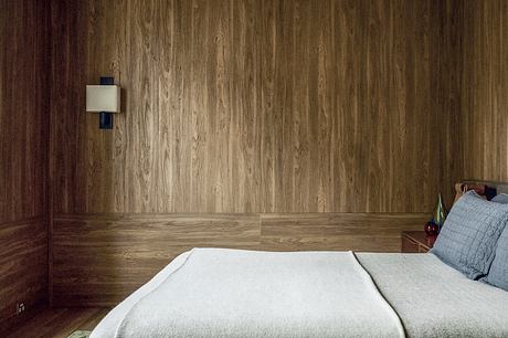 Warm-toned wood paneling, minimalist décor, and a cozy bedroom setup.