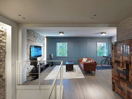 Modern open-concept living room with stone wall, built-in cabinets, and hardwood floors.