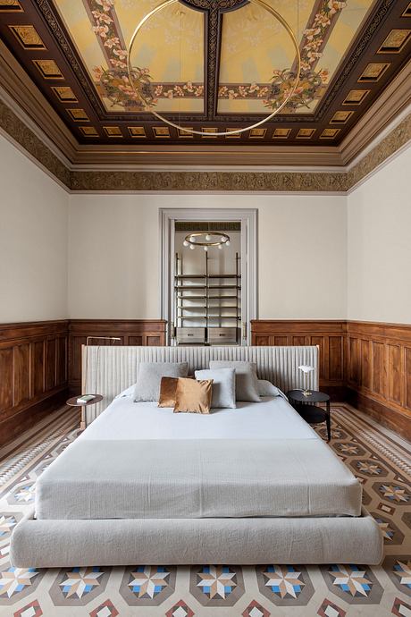 Ornate golden-trimmed ceiling, intricate tile floor, plush bedding, and sleek modern furnishings.