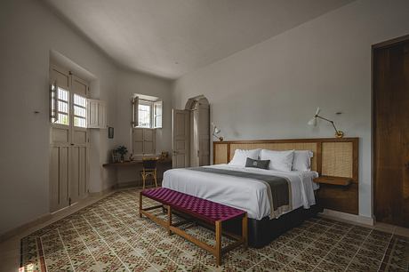 Cozy bedroom with wooden furniture, tiled floor, and large windows providing natural light.