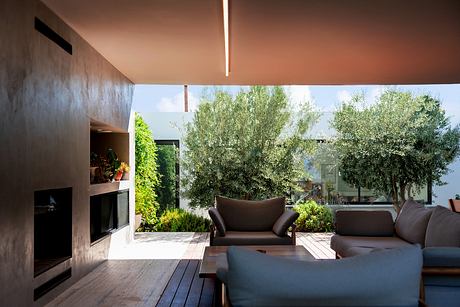 Spacious open-plan living area with wooden deck, large windows, and lush greenery.