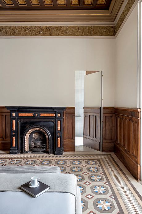 Ornate ceiling molding, intricate tile flooring, and a grand fireplace in a luxurious interior.