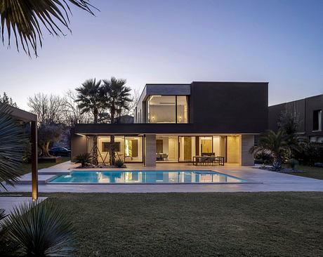 Modern, sleek home with expansive pool, lush landscaping, and inviting outdoor patio.