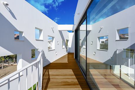 Modernist exterior with clean lines, large windows, and wooden deck against blue sky.