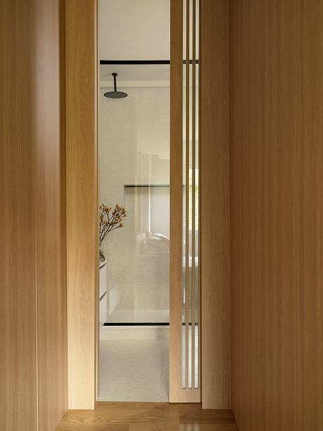 A minimalist bathroom with a wooden frame and sleek, modern shower head.