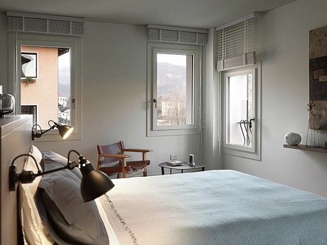 Cozy bedroom with minimalist furnishings, large windows, and serene mountain view.