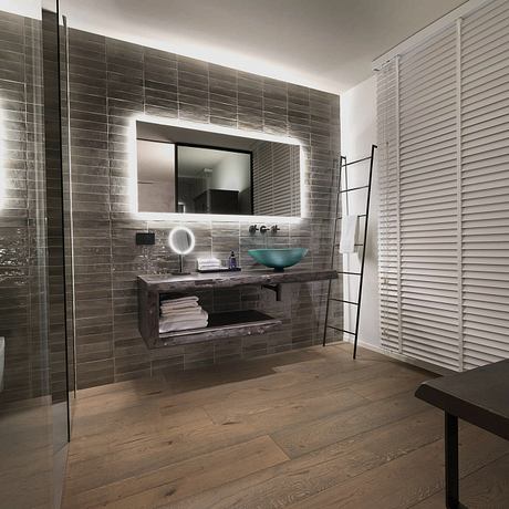 Sleek modern bathroom with dark tiled walls, wooden vanity, and glass shower enclosure.