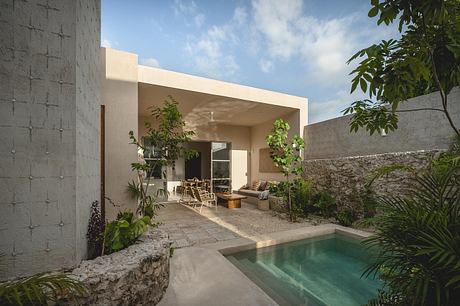 A modern, minimalist home with a small pool and lush foliage surrounding the outdoor living area.